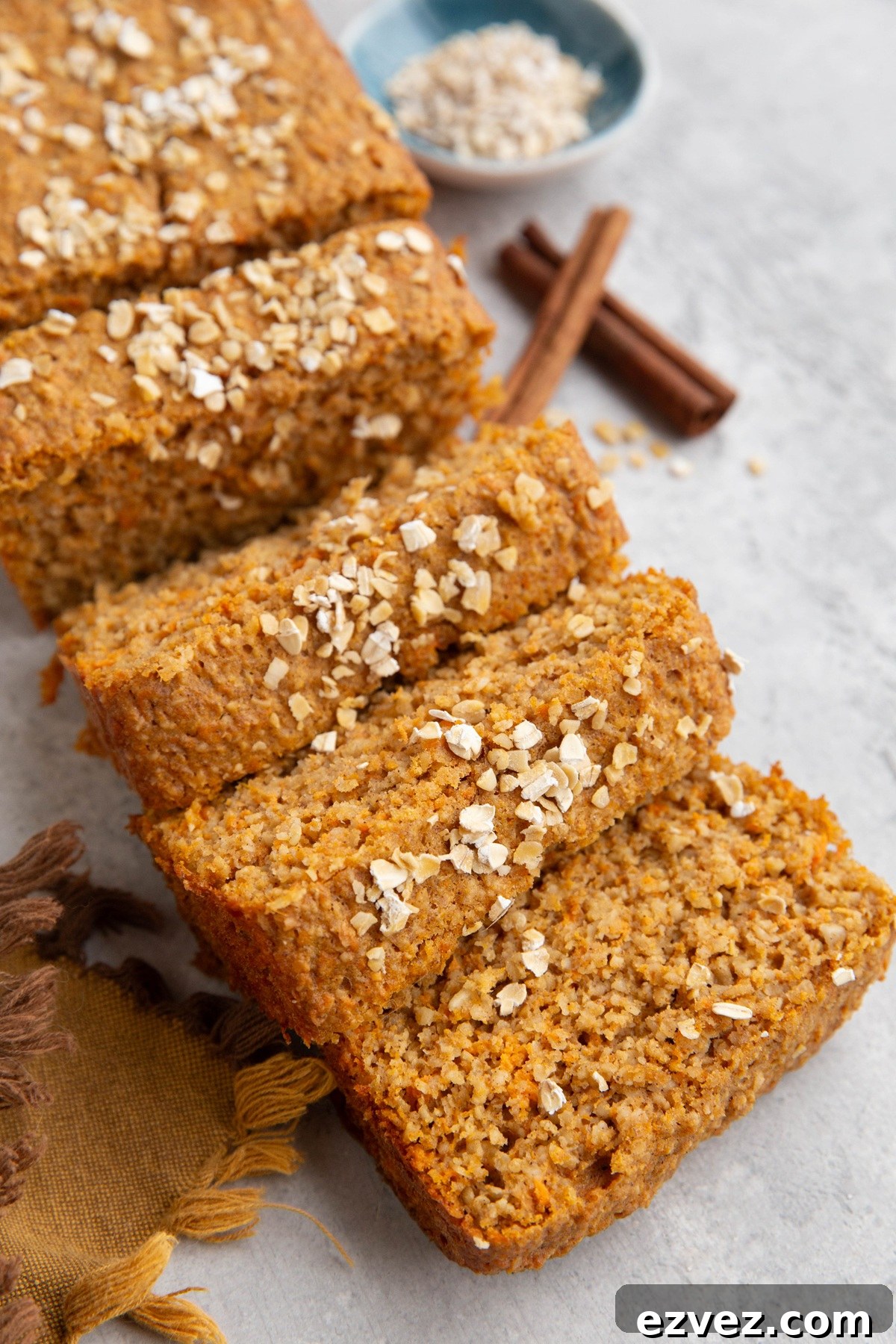 Loaf of sweet potato bread cut into slices with oats sprinkled on top.