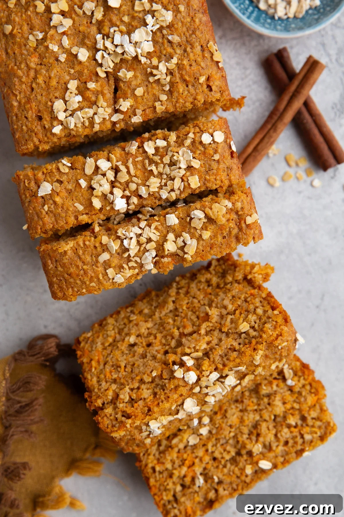 Loaf of sweet potato bread cut into slices with oats sprinkled on top.