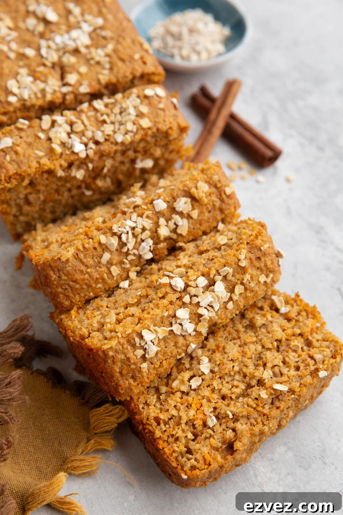 Loaf of sweet potato bread cut into slices with oats sprinkled on top.