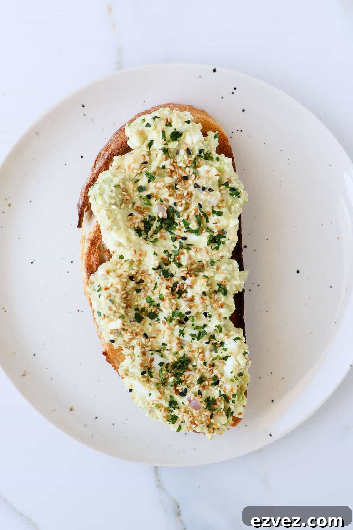 Cottage cheese avocado toast with sesame seeds and parsley on top.