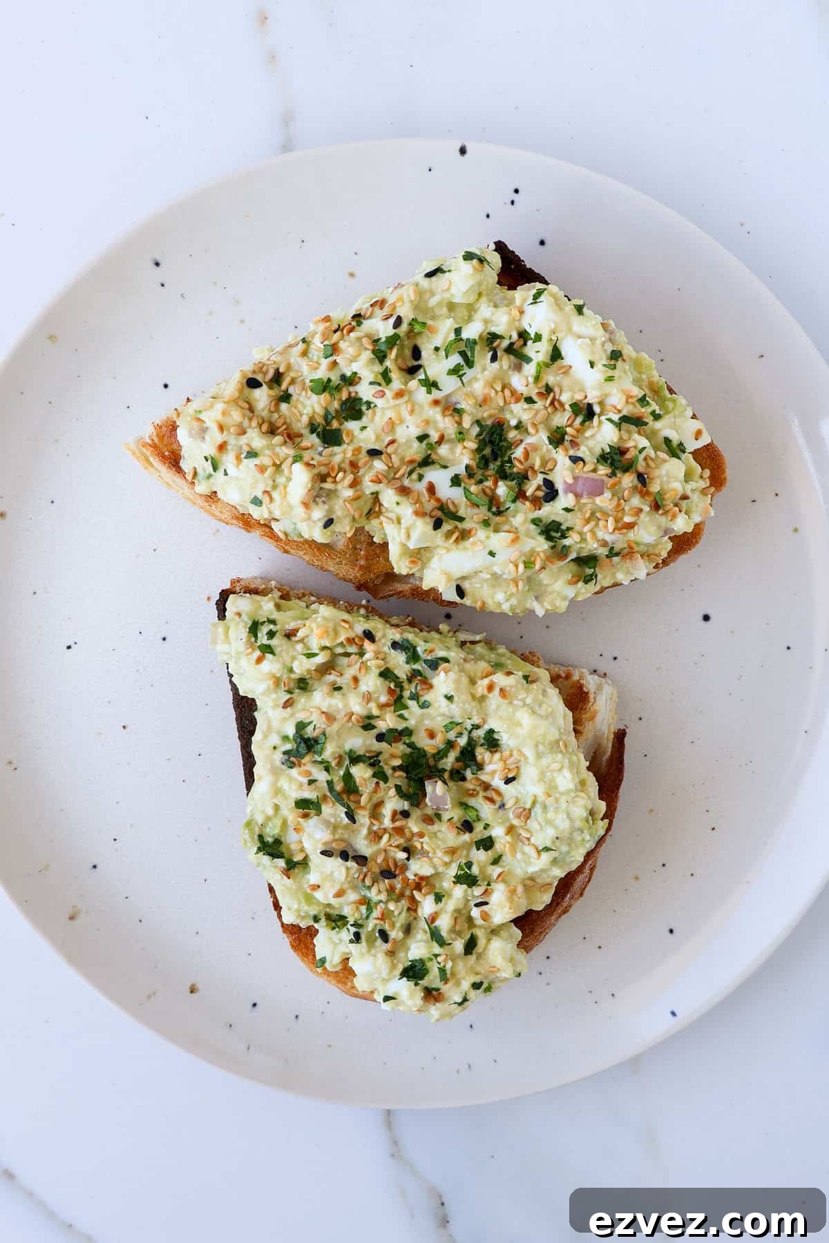 Cottage cheese avocado toast cut in half on a plate.