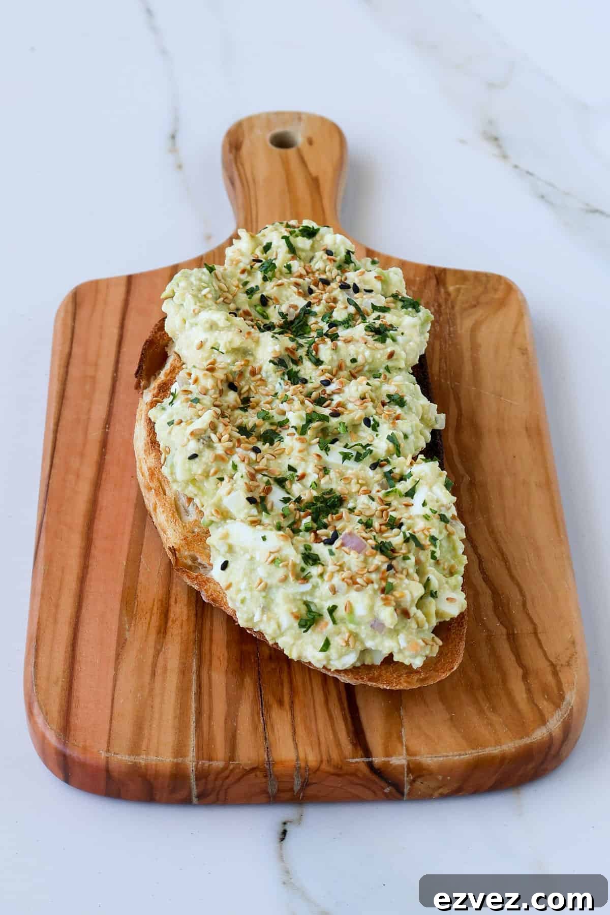 Side shot of cottage cheese avocado toast on a wooden board.