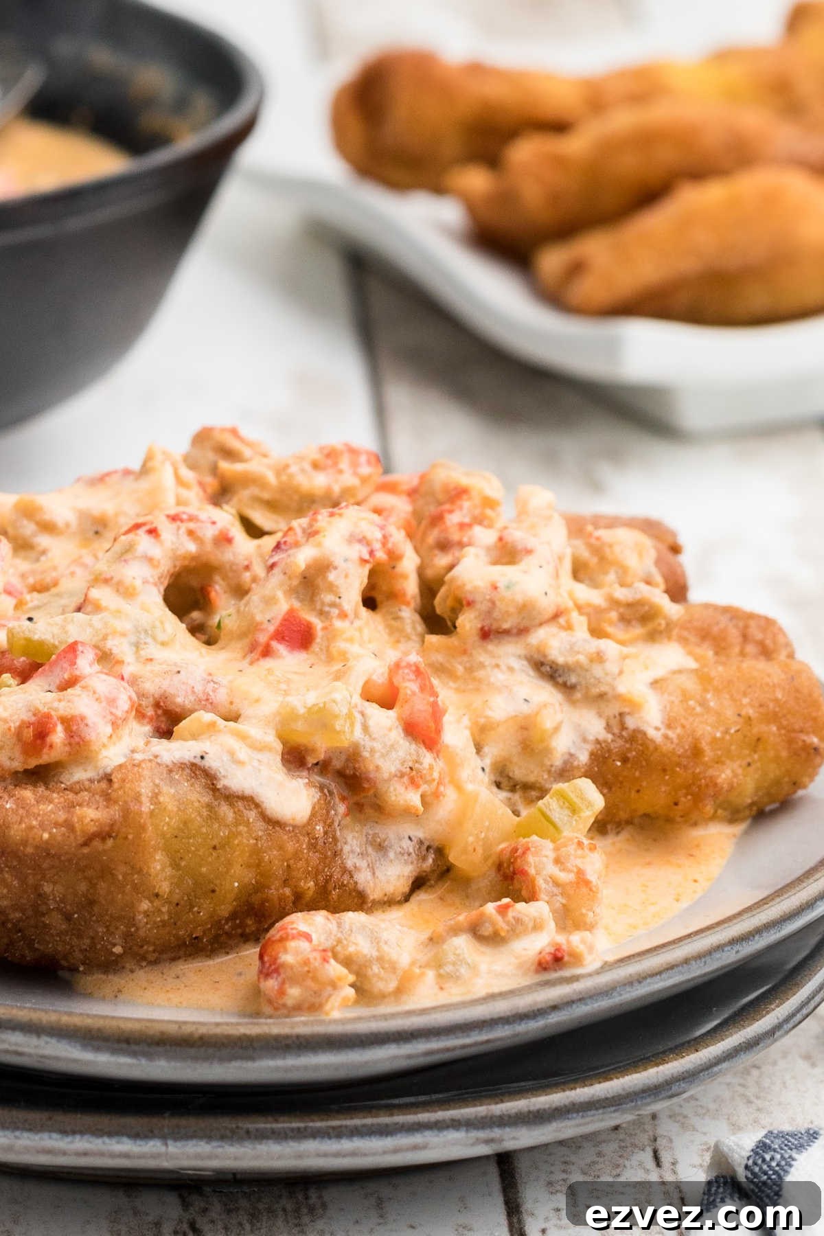 Very close up side view of crawfish sauce poured over a piece of fried fish.