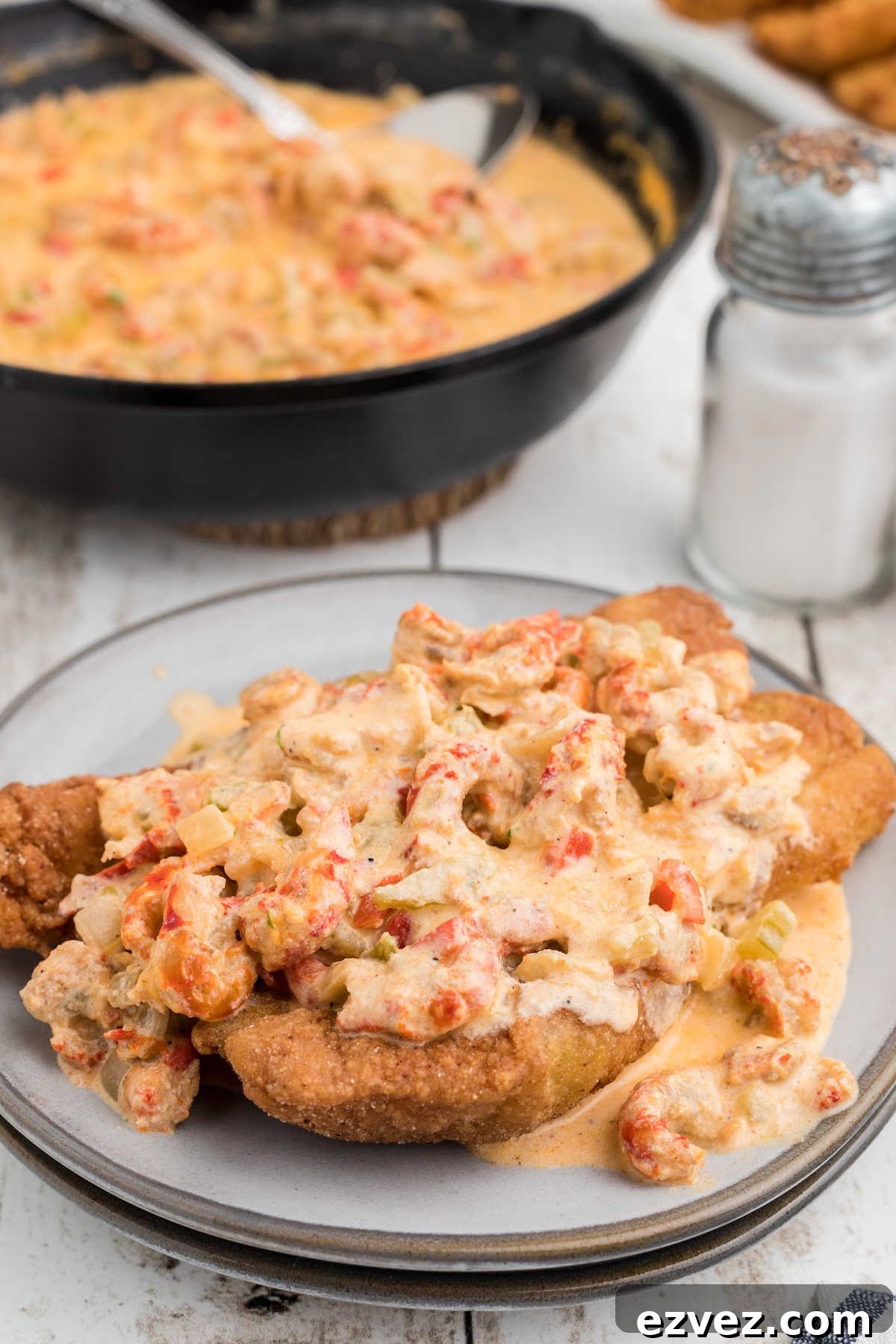 A piece of fried fish with crawfish sauce poured over the top.