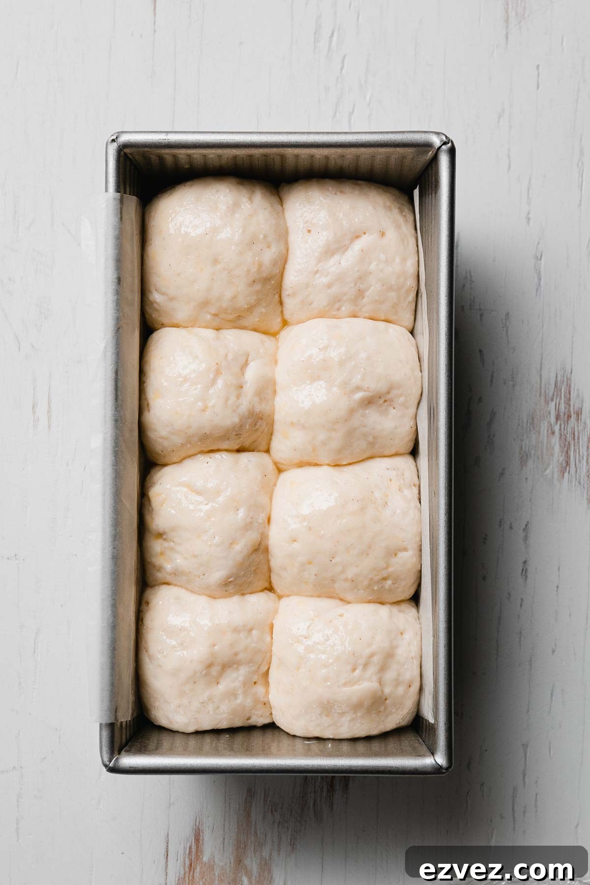 Gluten-free Hawaiian rolls after rising-puffed up and touching in the loaf pan, ready to bake.