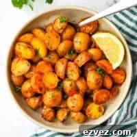 A bowl of roasted harissa potatoes garnished with parsley and a lemon wedge.