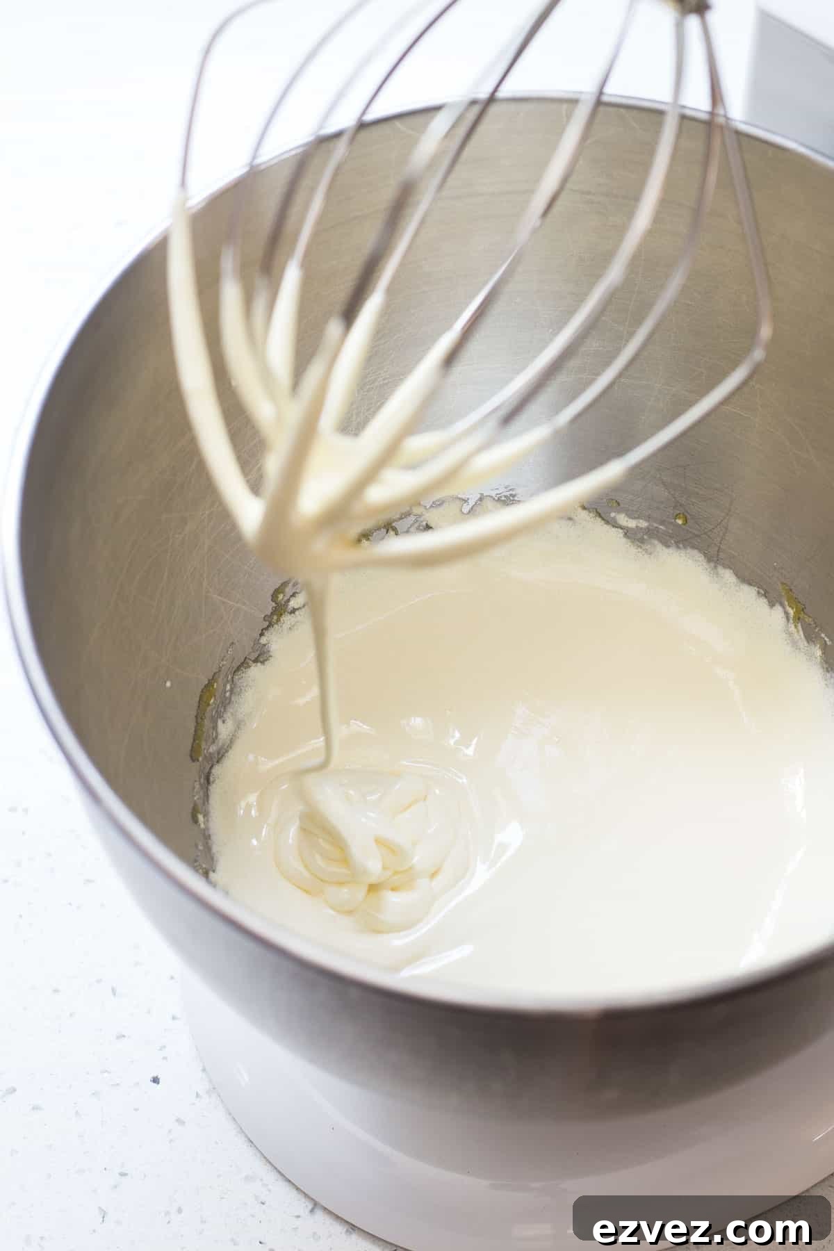 Eggs are beaten with sugar in a stand mixer bowl.