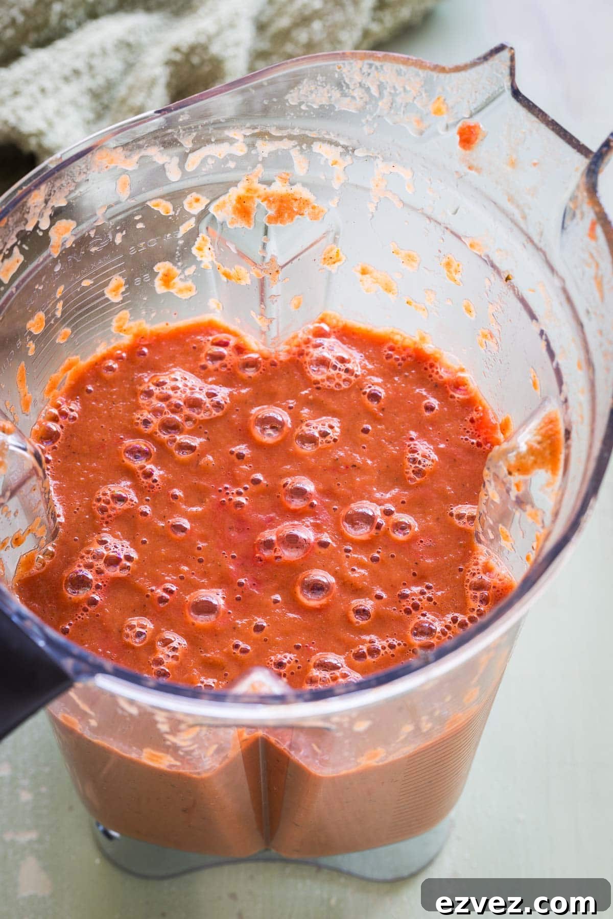 A blender full of chunky cooked tomato soup ready to be pureed.