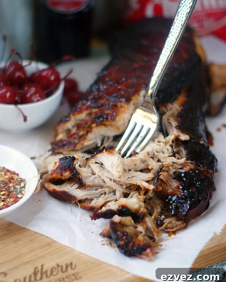A pork tenderloin being shredded with a fork.