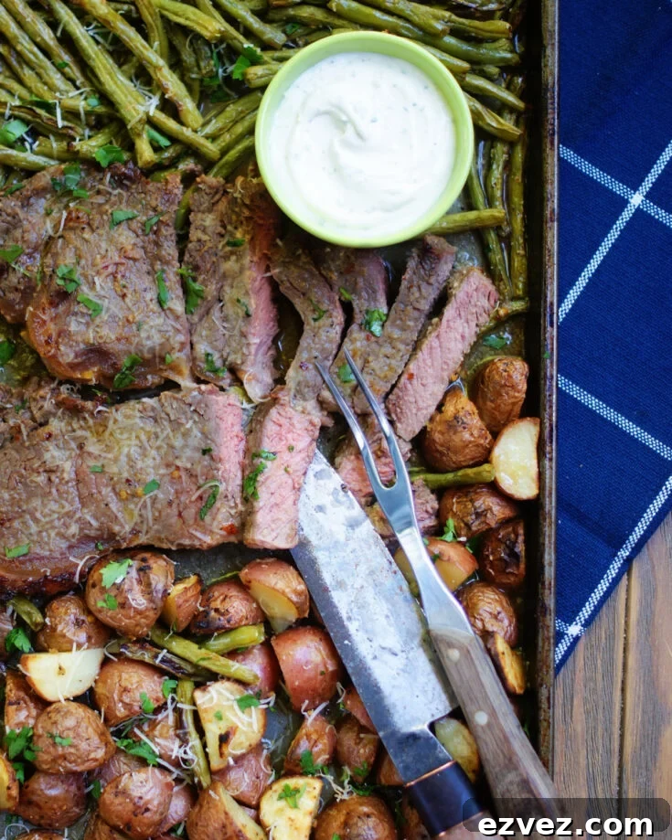 A close up of steak, potatoes, green beans cooked together on a sheet pan to show texture of the roasted vegetables and steak and the seasonings.