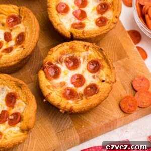 Golden crusted pizza cupcakes on a wooden cutting board with pepperoni scattered around the table.