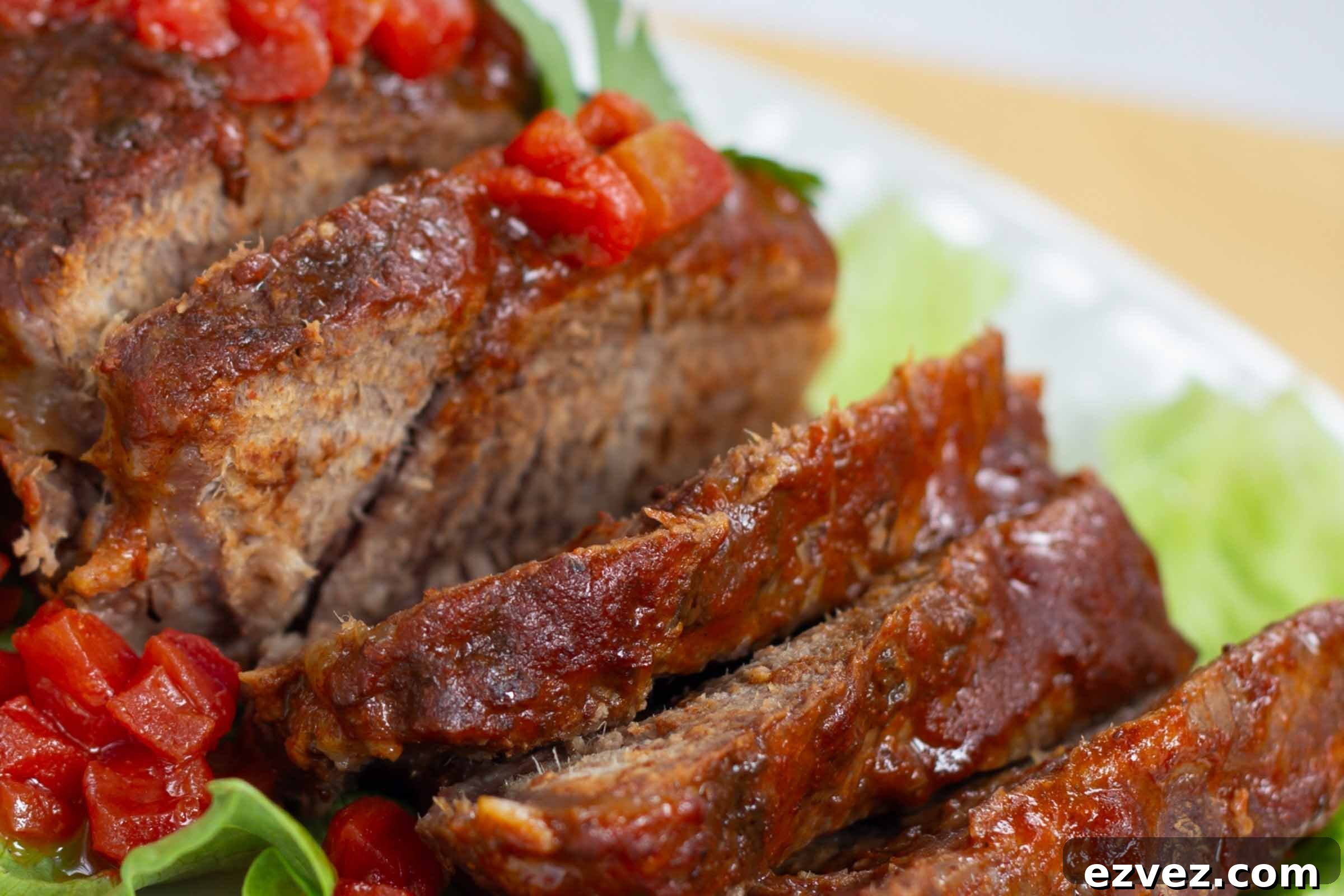 Sliced pot roast with diced tomatoes on top and a red sauce.