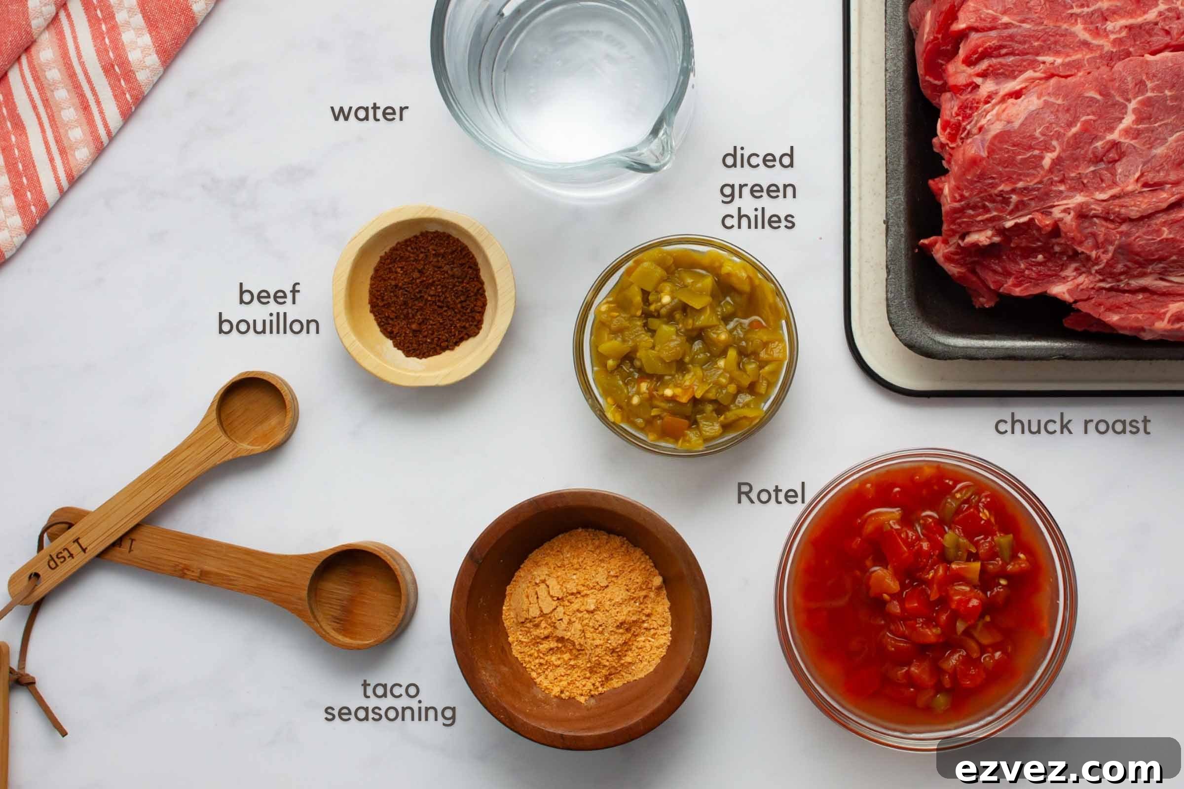 Ingredients on a counter: chuck roast, beef bouillon granules, water, diced green chiles, Rotel, and taco seasoning.