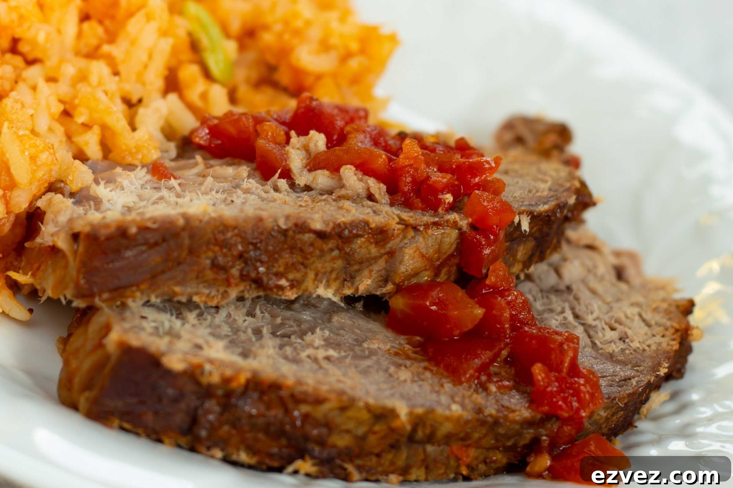 Slices of pot roast on a plate beside Mexican rice.