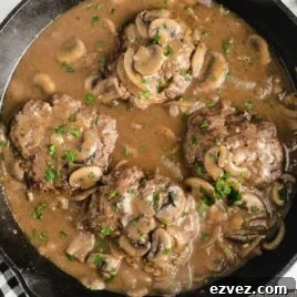 close up overhead shot of a skillet of Hamburger Steak garnished with parsley