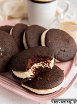 pink plate of chocolate whoopie pies with baileys buttercream frosting and one whoopie pie with a bite taken out of it