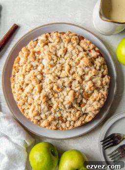Irish apple cake with crumble topping on a plate next to Granny Smith apples.