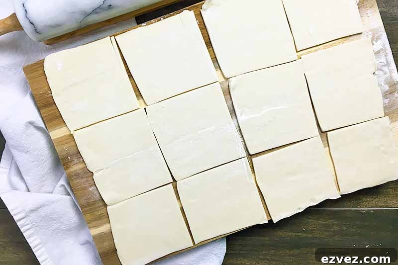 Horizontal image of 12 squares of puff pastry on a wooden board.