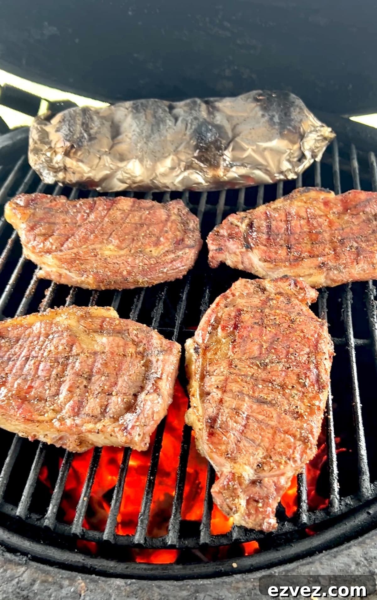 Grilling ribeye steaks with foil packet of potatoes.