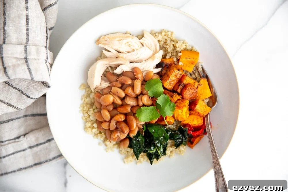 Overhead shot of a grain bowl with vegetables, chicken and pinto beans.