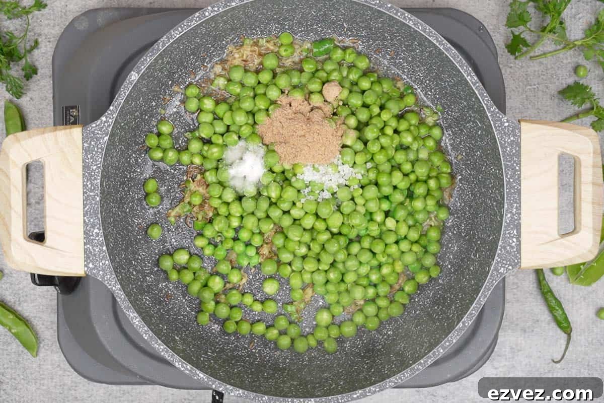 Green peas, salt, sugar and dry mango powder added to the pan.