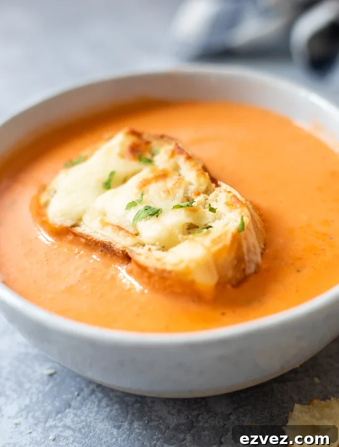 Tomato bisque soup in a bowl topped with cheesy toasted ciabatta