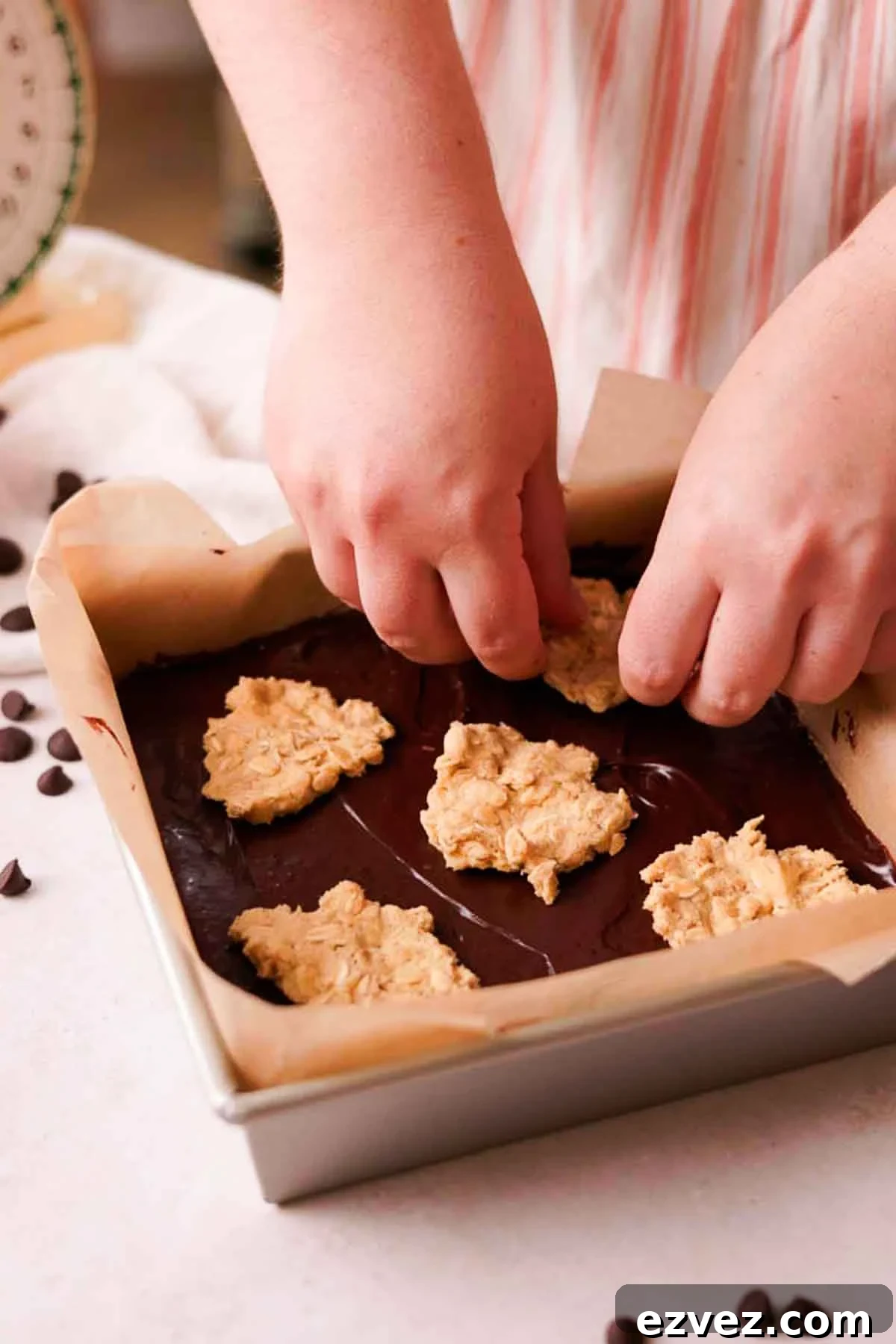 placing pieces of cookie dough on top of fudge in a pan