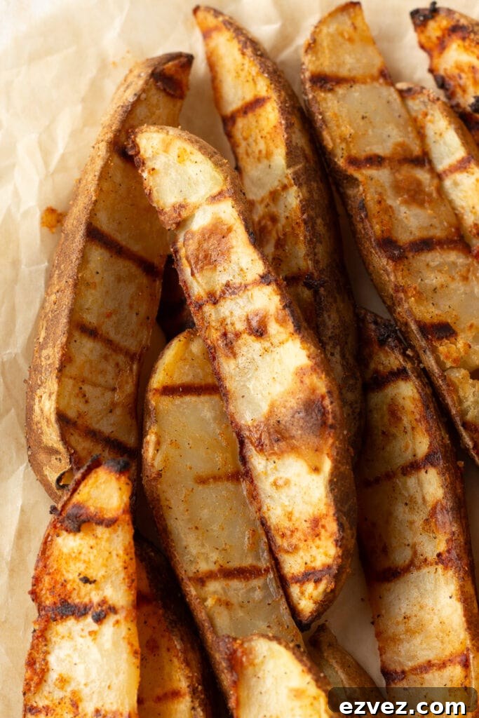 Close up of grilled potato wedges on brown parchment paper.