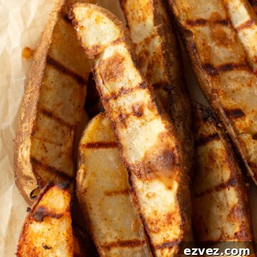 Close up of grilled potato wedges on brown parchment paper.