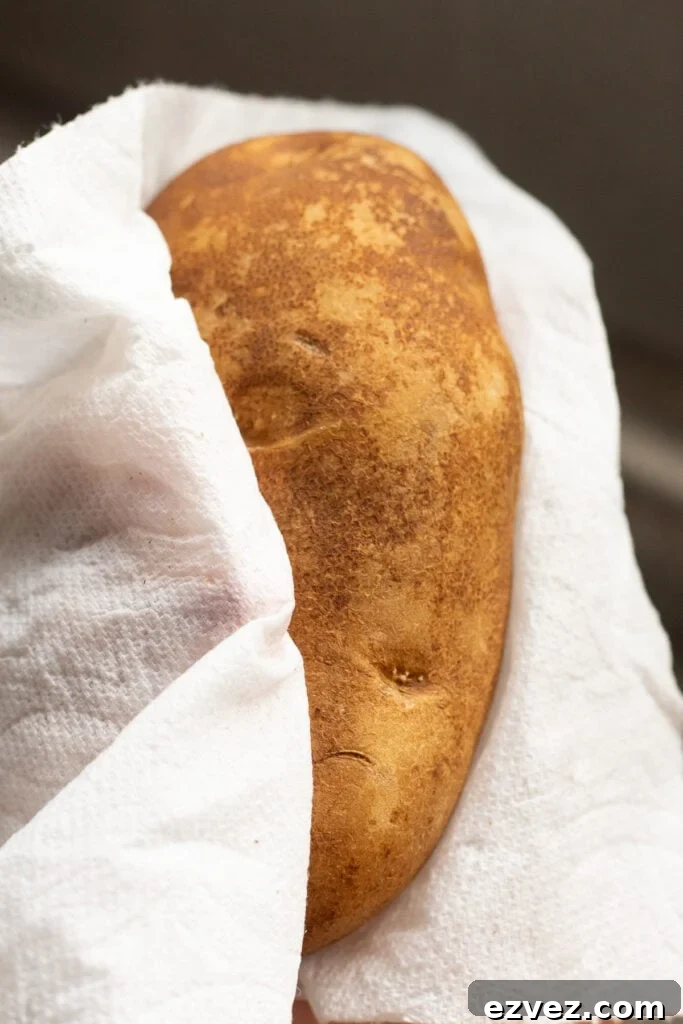 a washed russet potato being dried off with a paper towel.