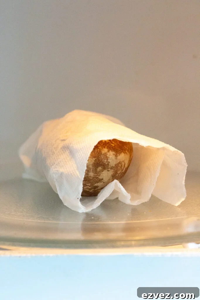 A russet potato wrapped in a damp paper towel in a microwave.