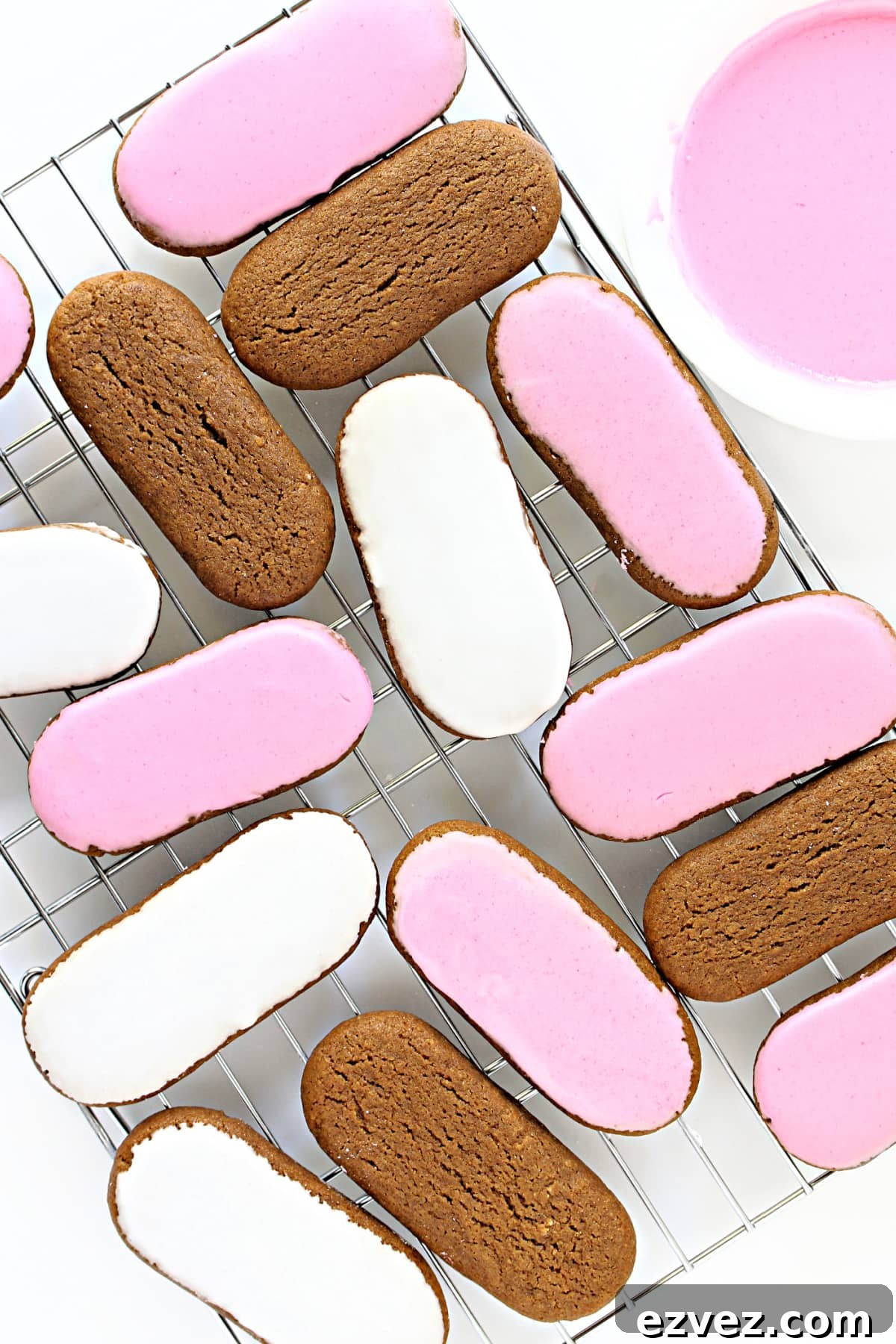 Irresistible Honey Jumbles Cookies Recipe for Crispy, Sweet Bites 2 Pink and white iced oval cookies on a wire cooling rack.