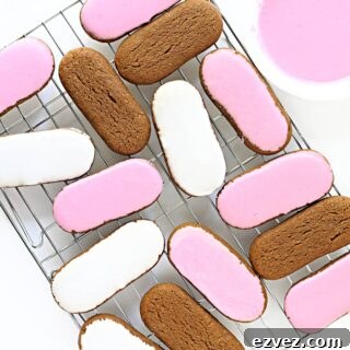 Pink and white iced oval Honey Jumble biscuits on a wire rack.
