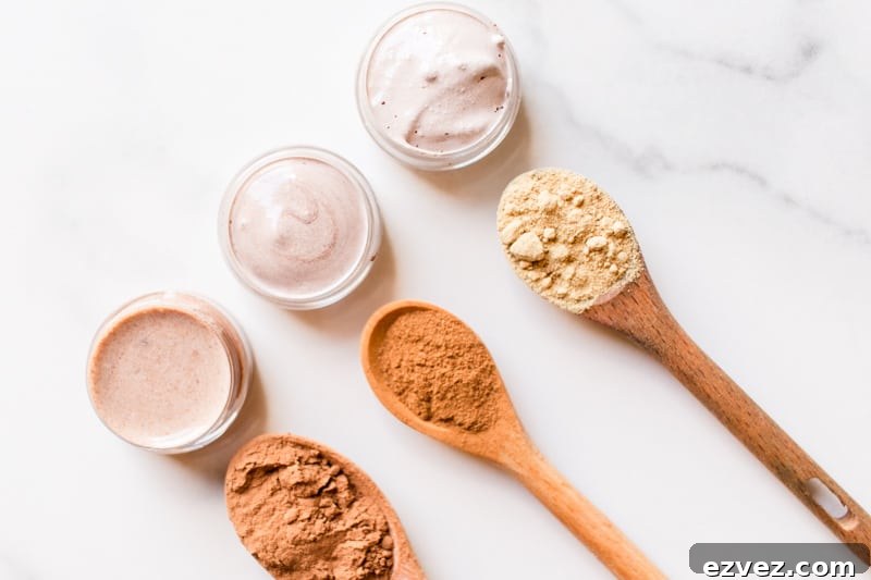 Top 3 best natural concealer recipes in small glass containers with the different color pigments in wooden spoons.