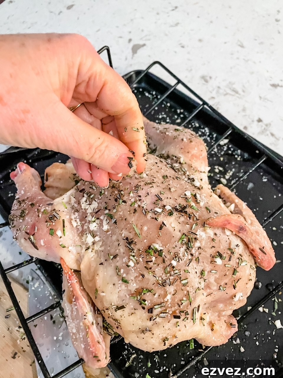 The uncooked chicken with the butter and spices rubbed into its surface
