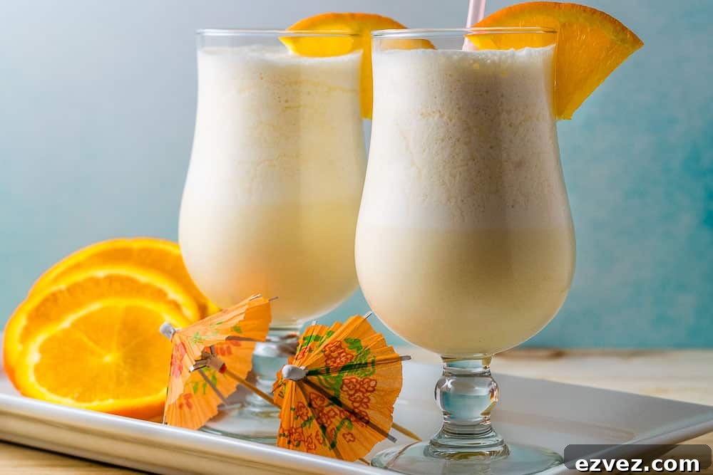 two orange creamsicle drinks in a platter with orange slices.