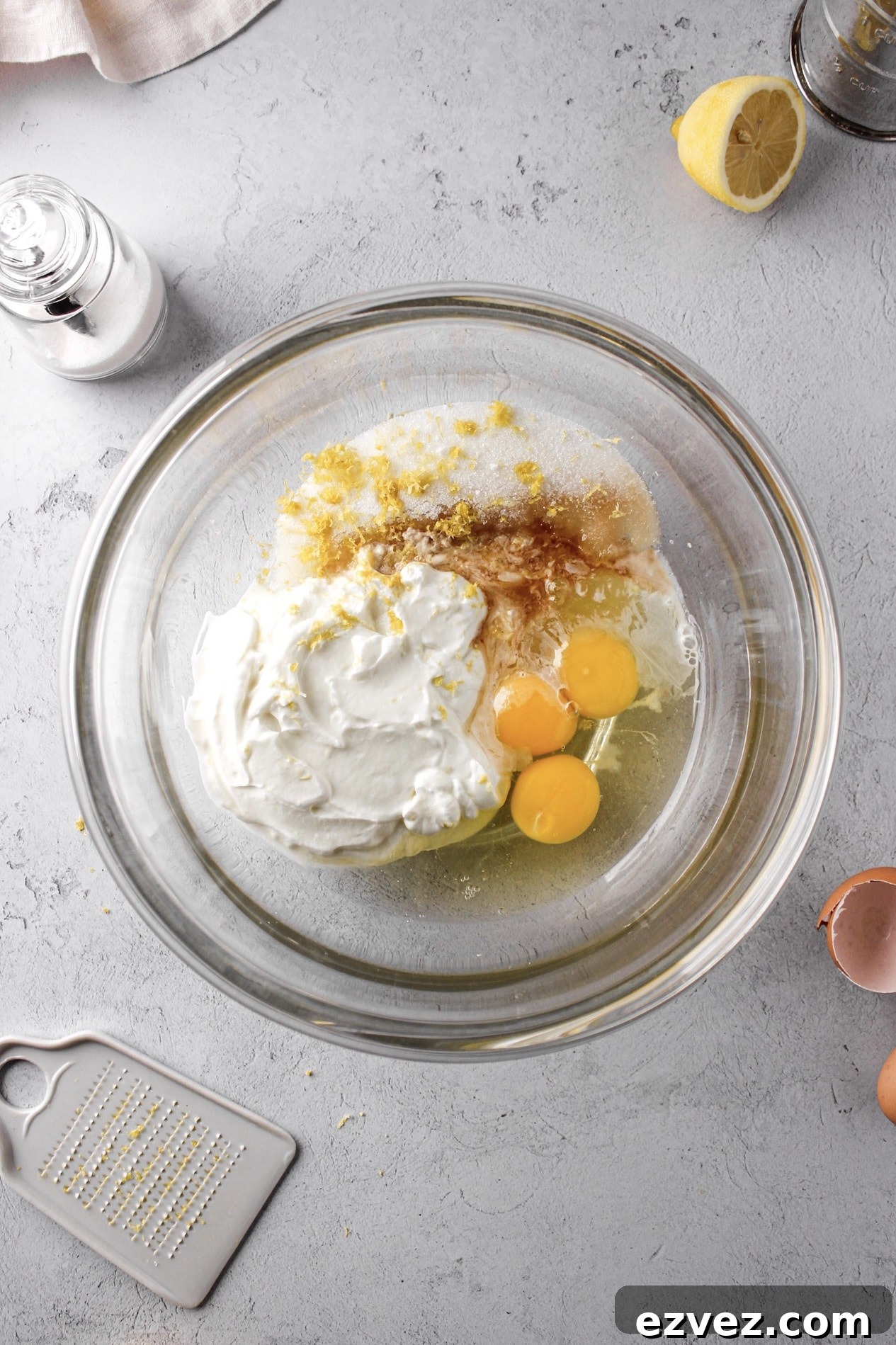 glass bowl of lemon pound cake ingredients with lemons, yogurt and eggs