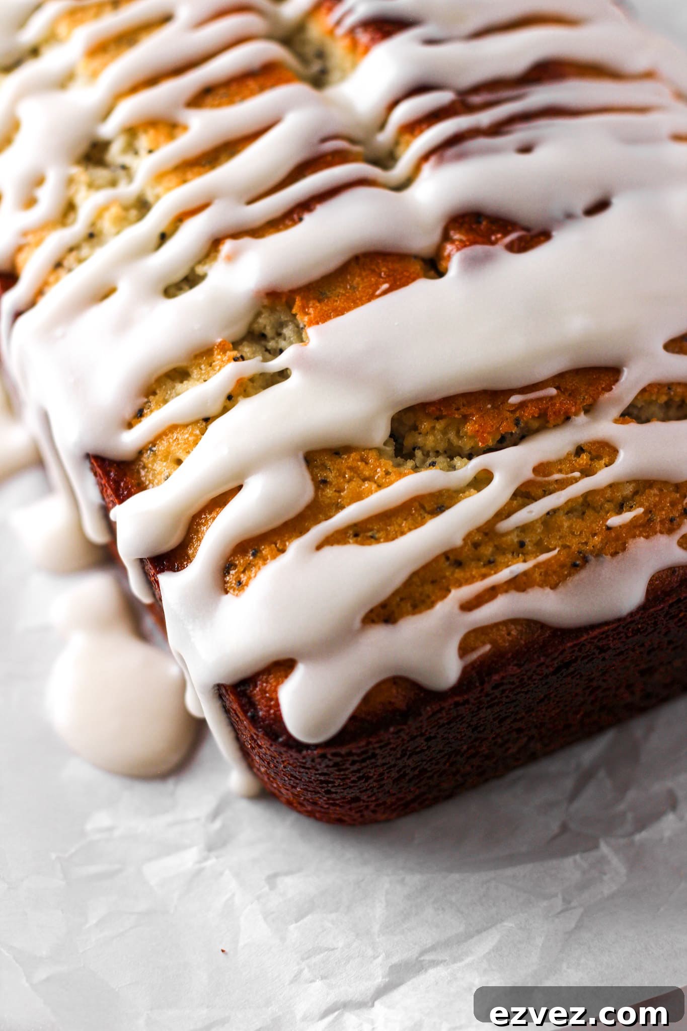 close up of a lemon glazed loaf on parchment paper for baked abundance blog