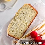 A slice of lemon poppy seed loaf cake with fresh raspberries and a simple glaze.