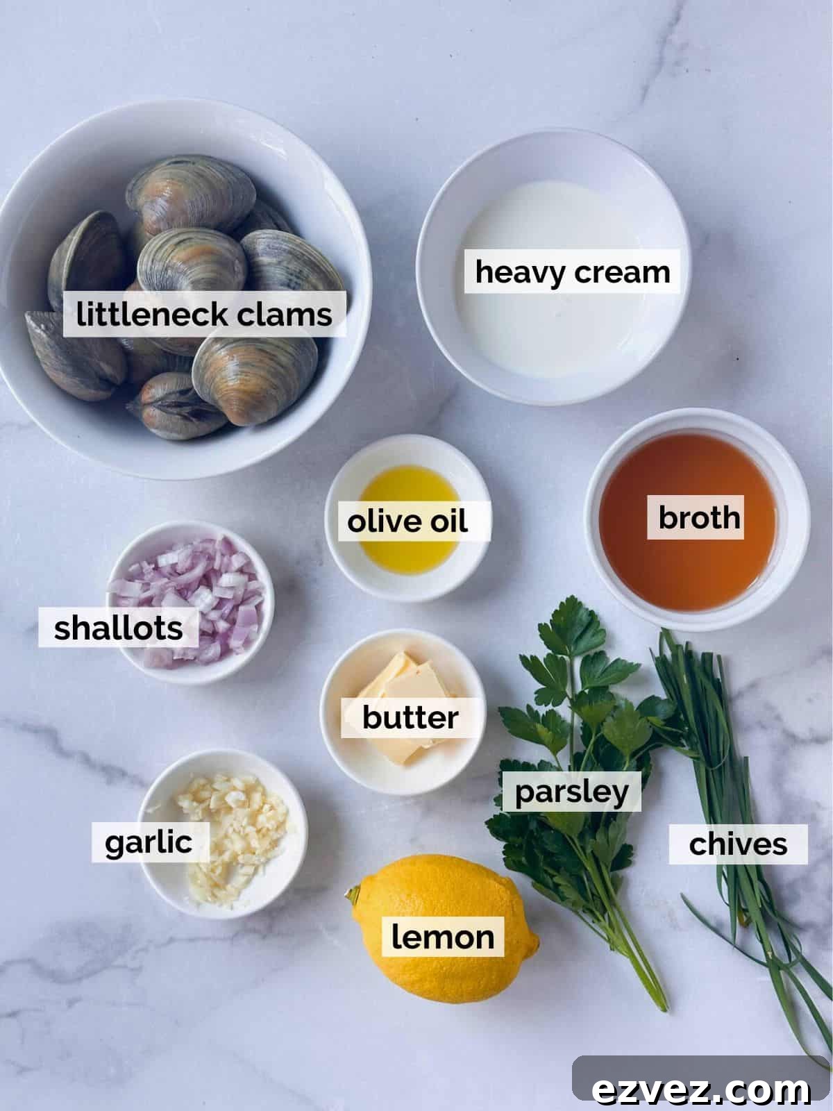 Ingredients for steamed littleneck clams on a white table.