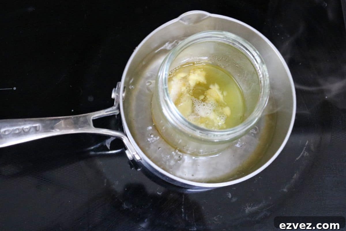 In process diy lotion image, small pot on stove with a mason jar of ingredients placed into the water