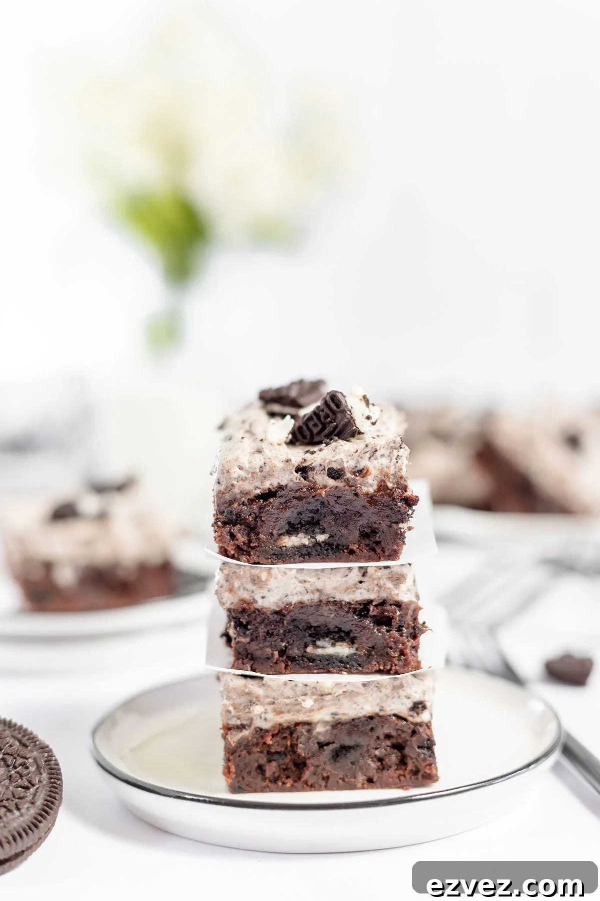 Cookies & Cream Brownies Recipe — Fudgy Oreo-Stuffed Brownies 2 Cookies and cream brownies stacked on a plate.