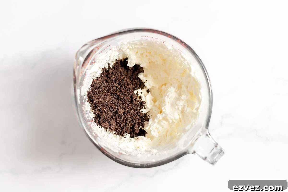 Cookies & Cream Brownies Recipe — Fudgy Oreo-Stuffed Brownies 12 Crushed Oreos mixed into cream cheese mixture in the bowl.