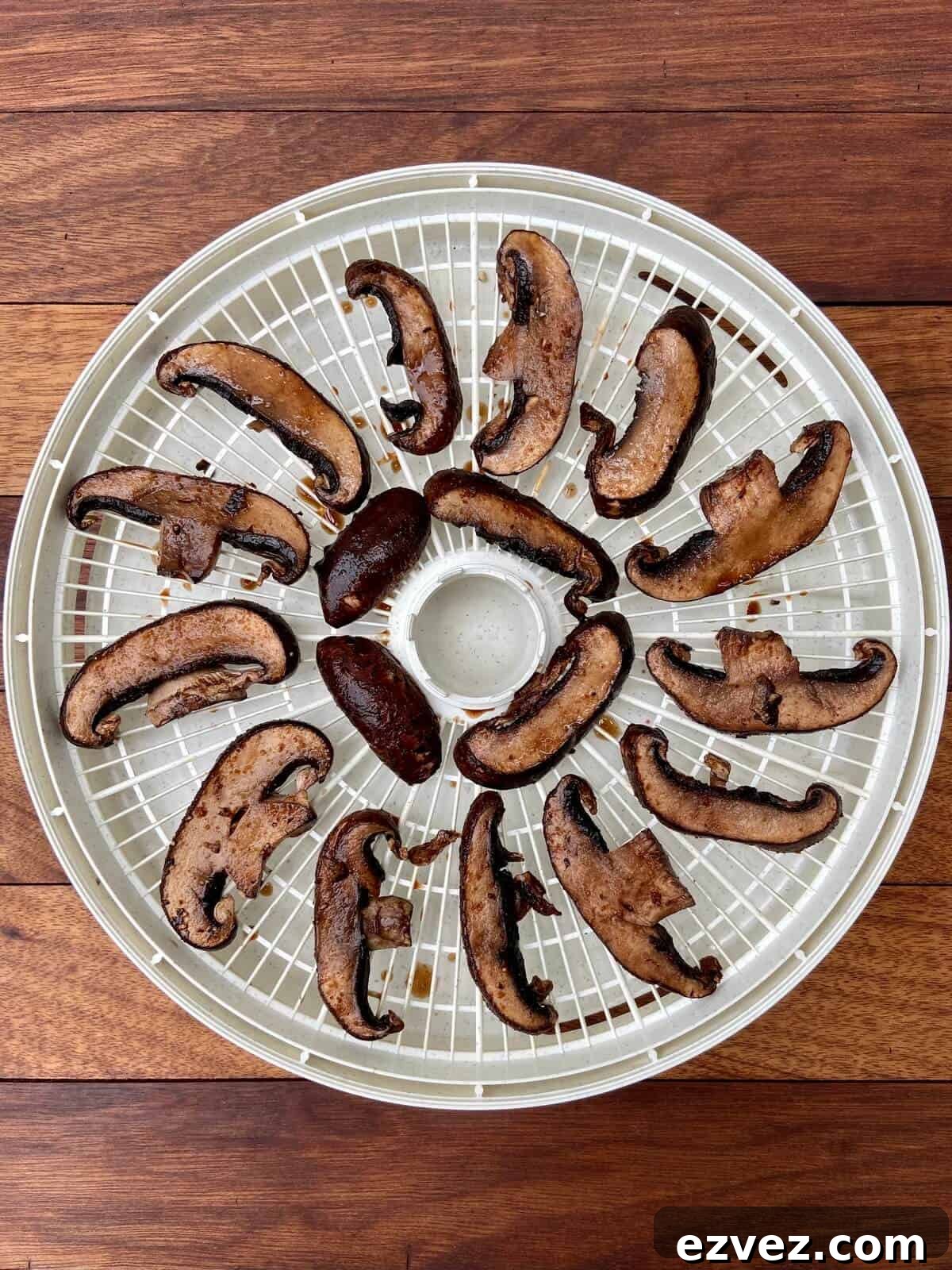 Sliced and marinated mushrooms on drying rack of food dehydrator.