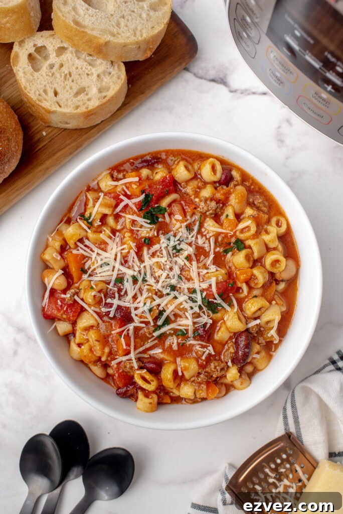A bowl full of pasta fagioli soup topped with grated Parmesan cheese.