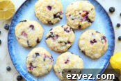 A plate of blueberry muffin cookies with a half of lemon and a whole lemon in opposite corners and blueberries scattered around the plate.
