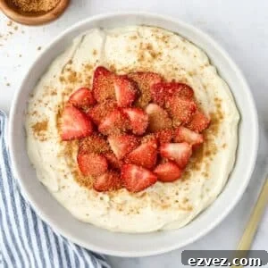 A bowl of fluffy yogurt topped with sliced strawberries and a sprinkling of graham cracker crumbs.