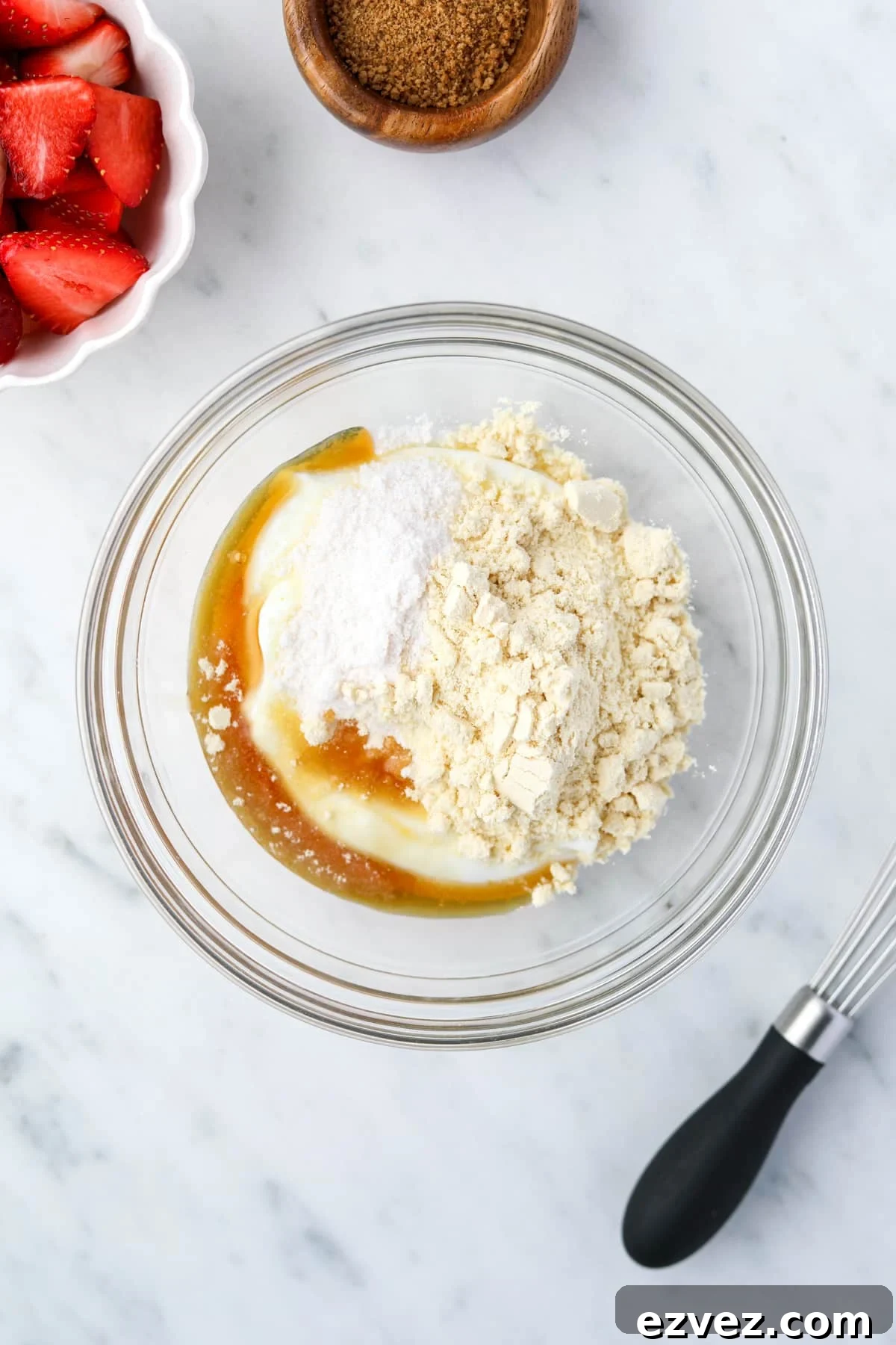 A bowl with yogurt, protein powder, maple syrup, pudding mix, and vanilla inside.