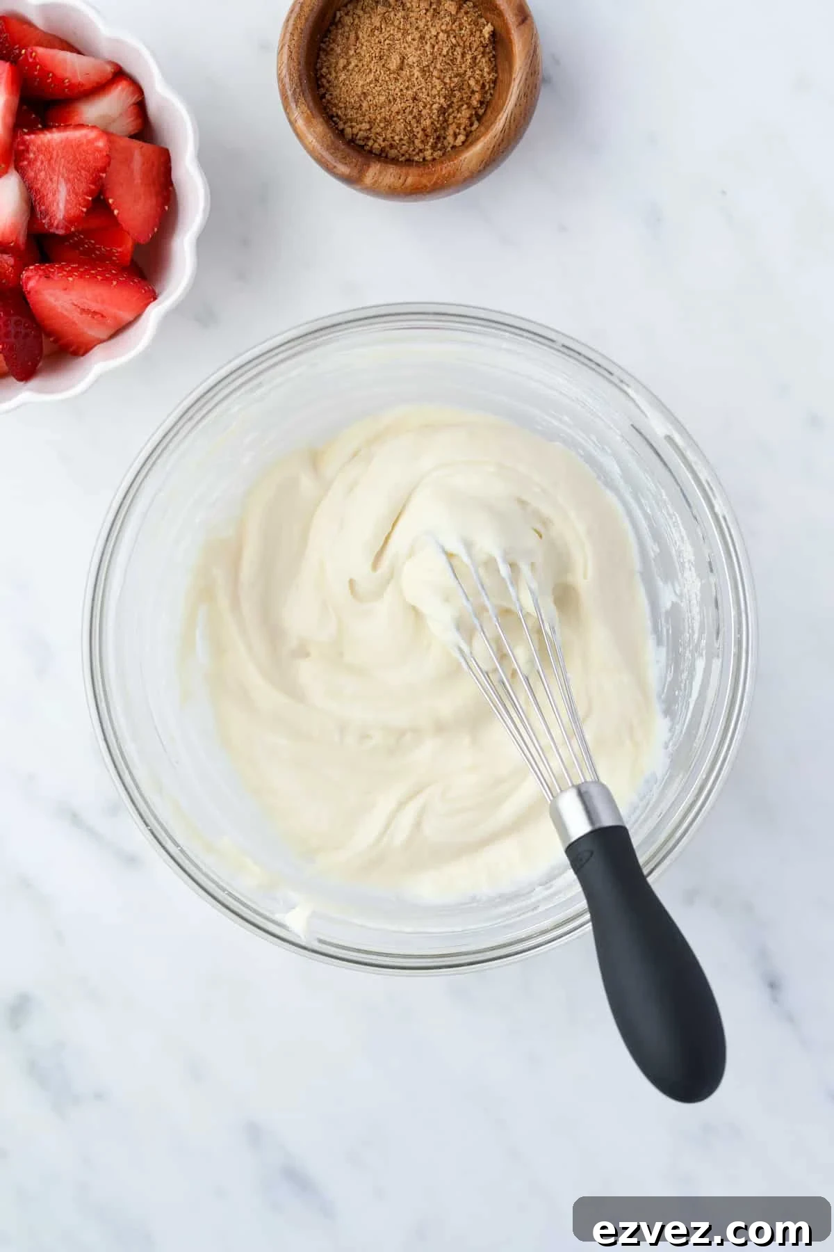 A bowl with creamy yogurt and a mini whisk.