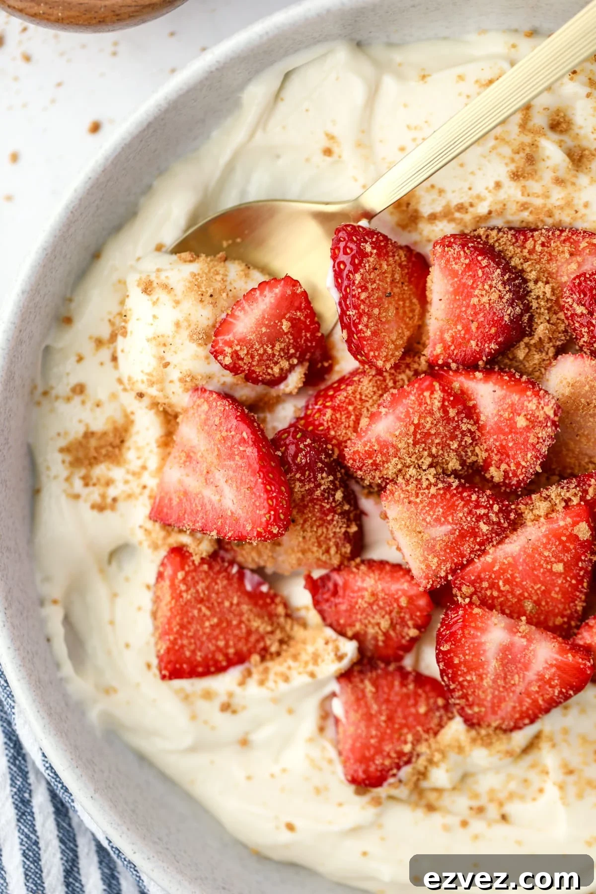 A spoon scooping creamy yogurt from a bowl topped with fresh sliced strawberries.